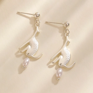 Boucles d'oreilles kangourou dorées avec perles ovales sur un fond crème minimaliste