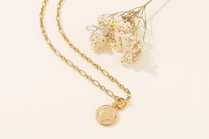 Detail of gold coin pendant necklace with Smart Brave Strong engraving and toggle clasp