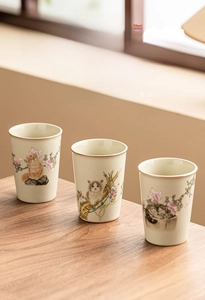 Close-up of Ru Kiln ceramic teacups with ice-crack glaze, cat and magnolia floral art