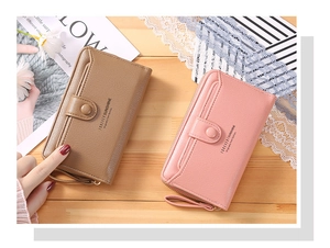 Detail of long leather wallets in pink and khaki featuring a wrist strap and zipper closure