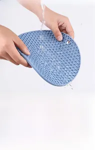 Washing soft blue silicone trivet with honeycomb pattern to show flexibility and water resistance