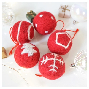Detailed close-up of handmade red wool felt Christmas ball ornaments with white patterns