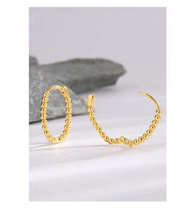 Macro detail of 14K gold plated sterling silver beaded hoop earrings with open closure