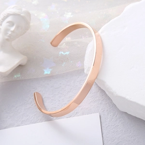 Polished rose gold C-shaped open bangle displayed on marble stone with elegant decor