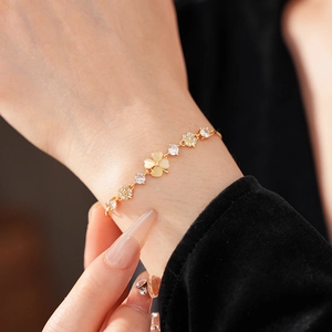 Macro detail of gold-plated clover bracelet with opal stone and zircon on a woman's wrist