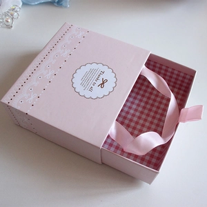 Pink drawer-style baby gift box featuring white lace patterns and a silk handle