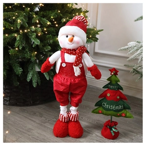 Macro shot of plush snowman doll with Merry Christmas tree and festive home decor
