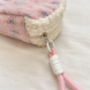 Detail of pink wool shell makeup bag featuring soft fleece stitching and woven zipper pull
