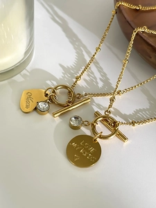 Detail of golden heart and round pendants with Mom engraving and crystal accent