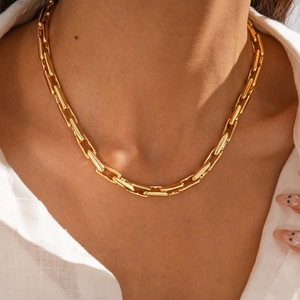 Close-up of golden paperclip link chain necklace worn on model for detail view