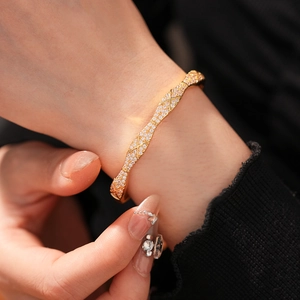 Detail of gold plated bangle with cross pattern and pavé cubic zirconia on model's wrist