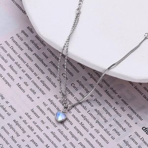 Detailed macro view of double-layer chain with heart moonstone pendant and silver finish