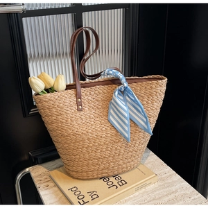 Detail of woven straw tote bag with brown PU handles and blue striped silk scarf