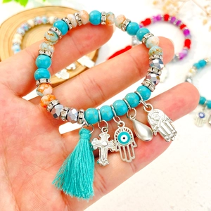 Detailopname van een Boheemse kralenarmband met Hamsa-hand en turquoise hangers