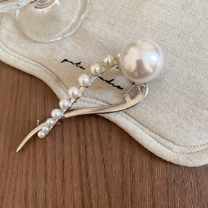Detail shot of elegant silver metal hair claw clip featuring ascending white pearls