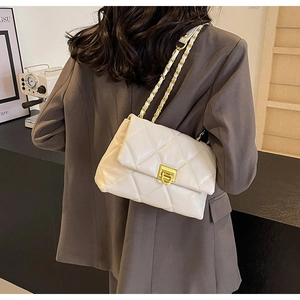 Close-up of white quilted crossbody bag with gold chain strap worn by a model