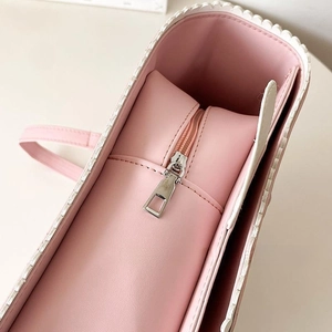Detail showing pink leather texture, wavy edge design and silver metal zipper on the bag