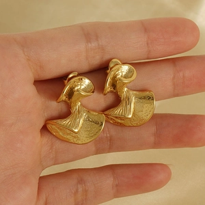 Makroaufnahme goldener fächerförmiger Ohrstecker mit Hammerschlag-Textur in der Hand
