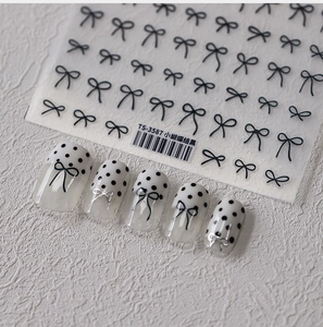 Detail of minimalist black line bow nail stickers on white polka dot false nails