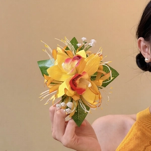 Elegant yellow gradient fabric orchid hair clip with green leaves held by a model