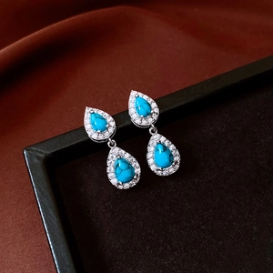 Macro shot of vintage silver earrings with turquoise drop pendants and pavé zircon stones