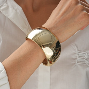 Detailed view of wide gold open cuff bracelet with high-polish mirror finish on model