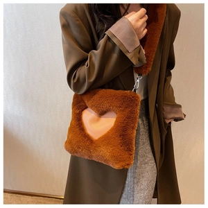 Dettaglio borsa a tracolla in ecopelliccia marrone con cuore rosa e catena in metallo