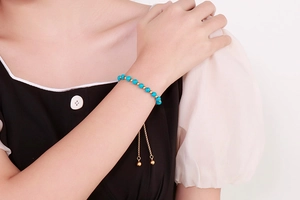 Détail d'un bracelet ajustable en turquoise et perles dorées sur un poignet
