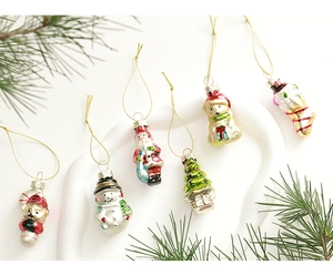 Assorted glass Christmas ornaments featuring Santa, snowman and bear on festive pine needles