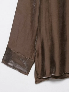 Detail view of dark brown satin fabric showing metallic luster and precise cuff stitching