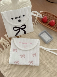 Detail view of quilted fabric sanitary pouch with bow embroidery and carry handle