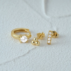 Detail view of gold-tone earring set with white zircons and minimalist bead studs