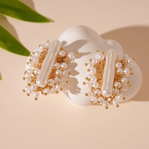Detailed view of French vintage gold pearl earrings on a white cloud display stand