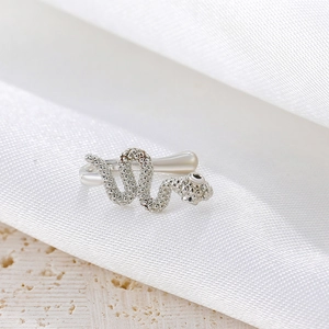 Close-up of silver snake-shaped non-piercing nose clip with textured details and black eyes