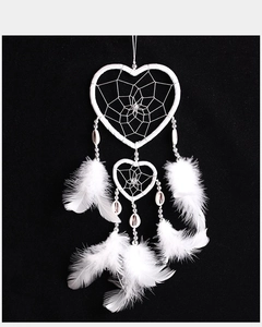 Detailed view of white heart-shaped dreamcatcher with hanging feathers and shell accents