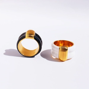 Modern wide black and white enamel rings with vertical gold ridges on a white background