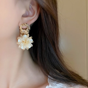 Gros plan de boucles d'oreilles fleurs en acrylique avec anneaux dorés sur modèle