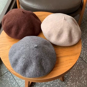 Three premium wool beret hats in coffee, beige, and grey displayed on a wooden table