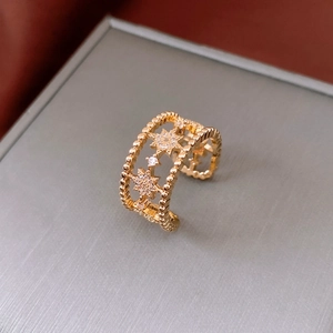 Detail of gold open ring with star cutout design and sparkling white zircon stones