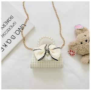 Detailed shot of beige houndstooth girls handbag with lace bow and pearl handle