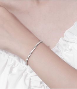 Close-up of a silver 2.5mm moissanite tennis bracelet worn on a woman's wrist