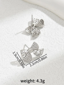 Detail view of silver bow earrings with inlaid zircons showing 1.5cm by 2.2cm dimensions