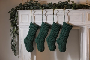 Detail of four dark green knitted Christmas stockings with classic cable stitch patterns