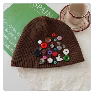 Detailed close-up of brown knit beanie with colorful decorative buttons on a cafe table