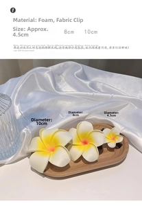 Detailed view of three sizes of yellow plumeria foam flower clips on a wood tray