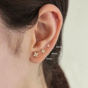 Three-piece set of gold flower stud earrings in 3mm, 4mm, and 5mm sizes shown on ear