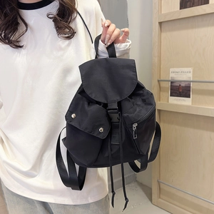 Detail of a black nylon backpack featuring drawstring closure and functional snap pockets