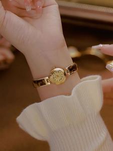 Macro shot of gold quartz watch with amber tortoiseshell chain strap on woman wrist