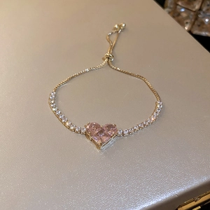 Close-up of adjustable gold bracelet featuring a pink heart zircon and tennis chain detail