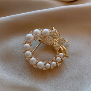 Elegant gold butterfly brooch with pearls and rhinestones on beige silk background